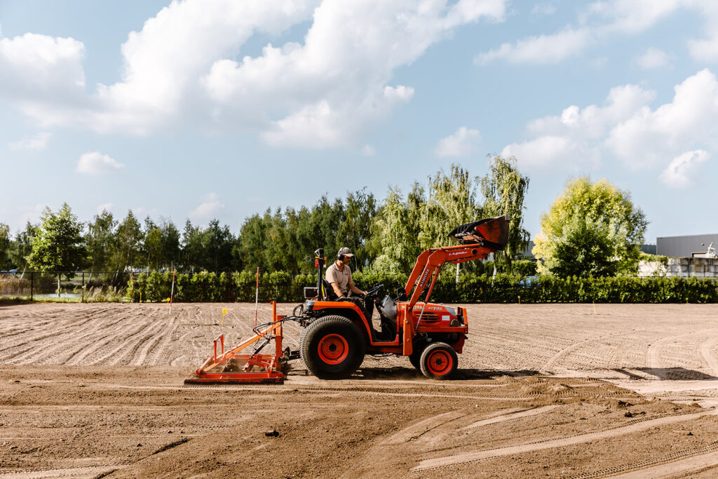 Traktor egalisiert den Boden, um eine optimale Grundlage für die Verlegung von Rollrasen zu schaffen. Die Bodenbearbeitung verbessert die Durchlässigkeit und Nährstoffaufnahme.