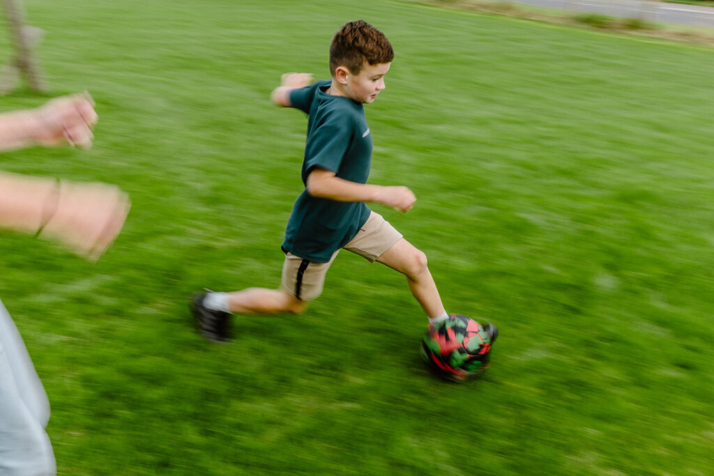 Kind spielt Fußball auf einem robusten Sportrasen. Der dichte und widerstandsfähige Rasen ist ideal für sportliche Aktivitäten und hohe Beanspruchung.