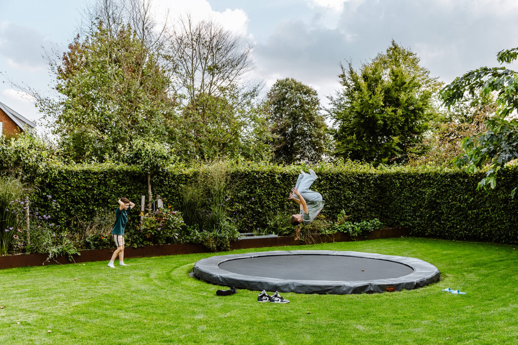 Kinder, die den schönen Rasen genießen und darauf spielen und auf dem Trampolin springen.